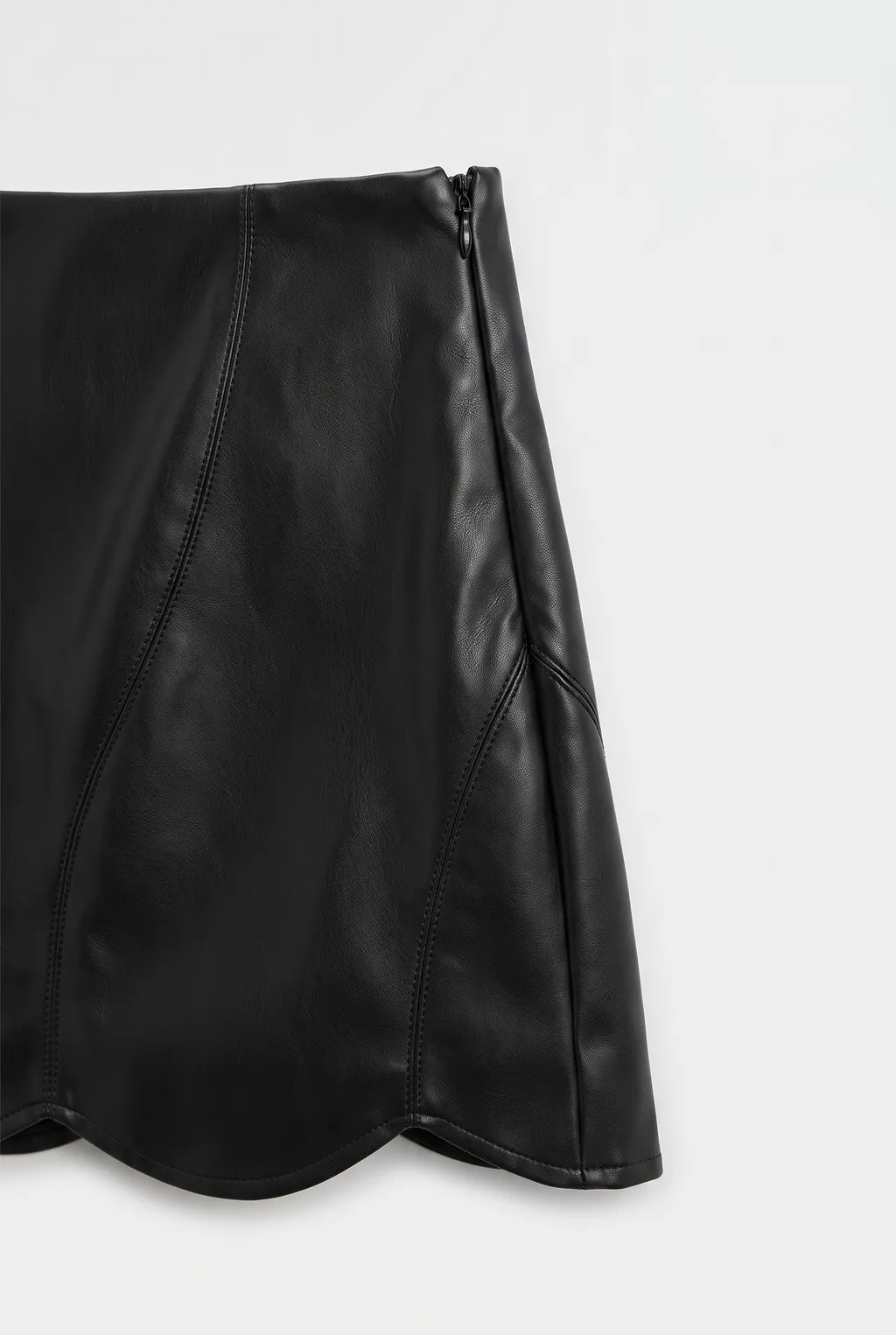 Black leather A-line skirt with a scalloped hem, on a white background