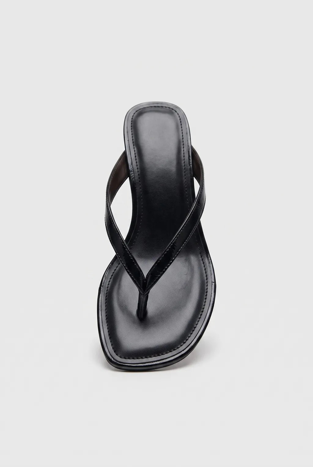 Black leather thong sandal with a low block heel, on a white background