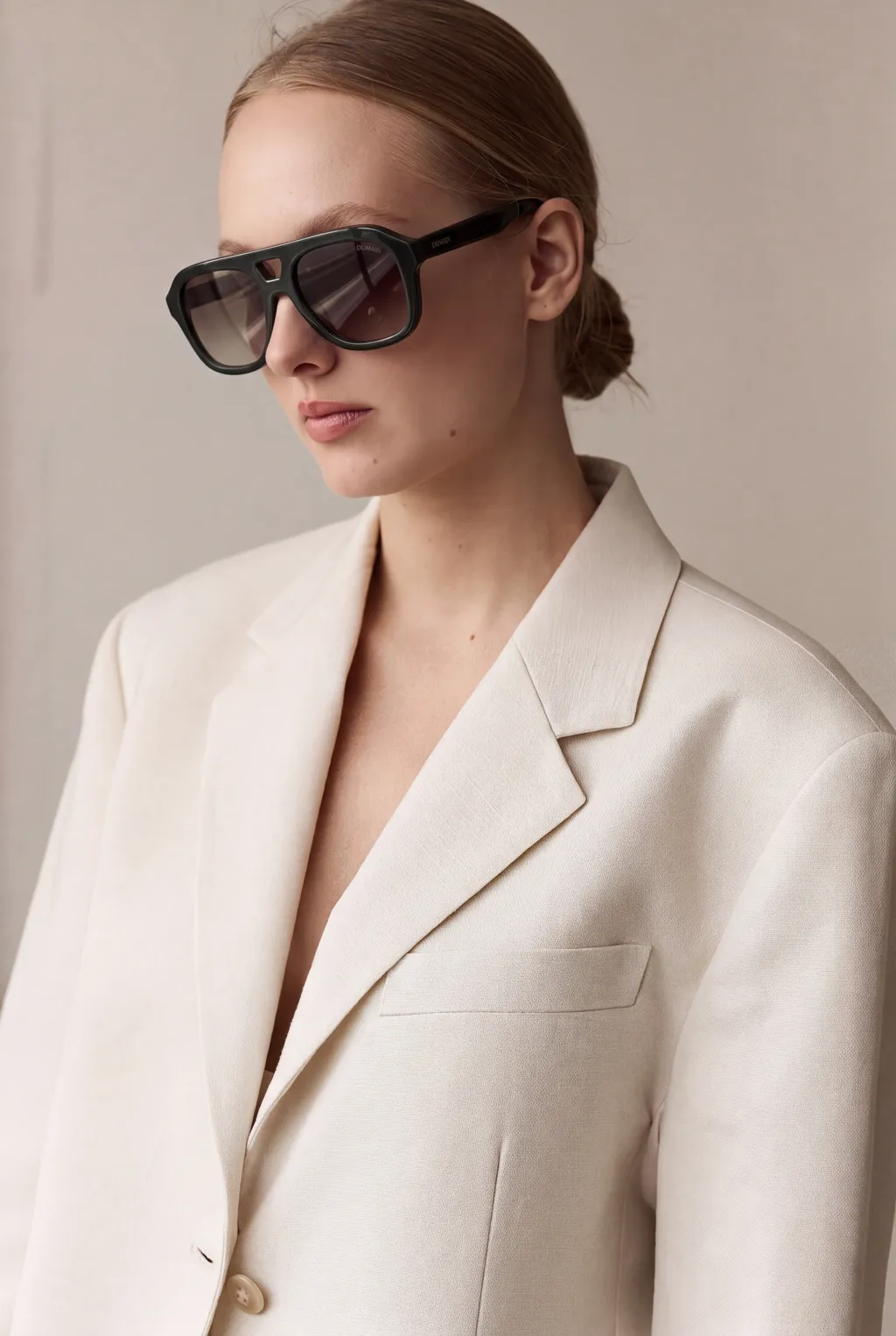 Model in an oversized cream blazer wearing dark aviator sunglasses