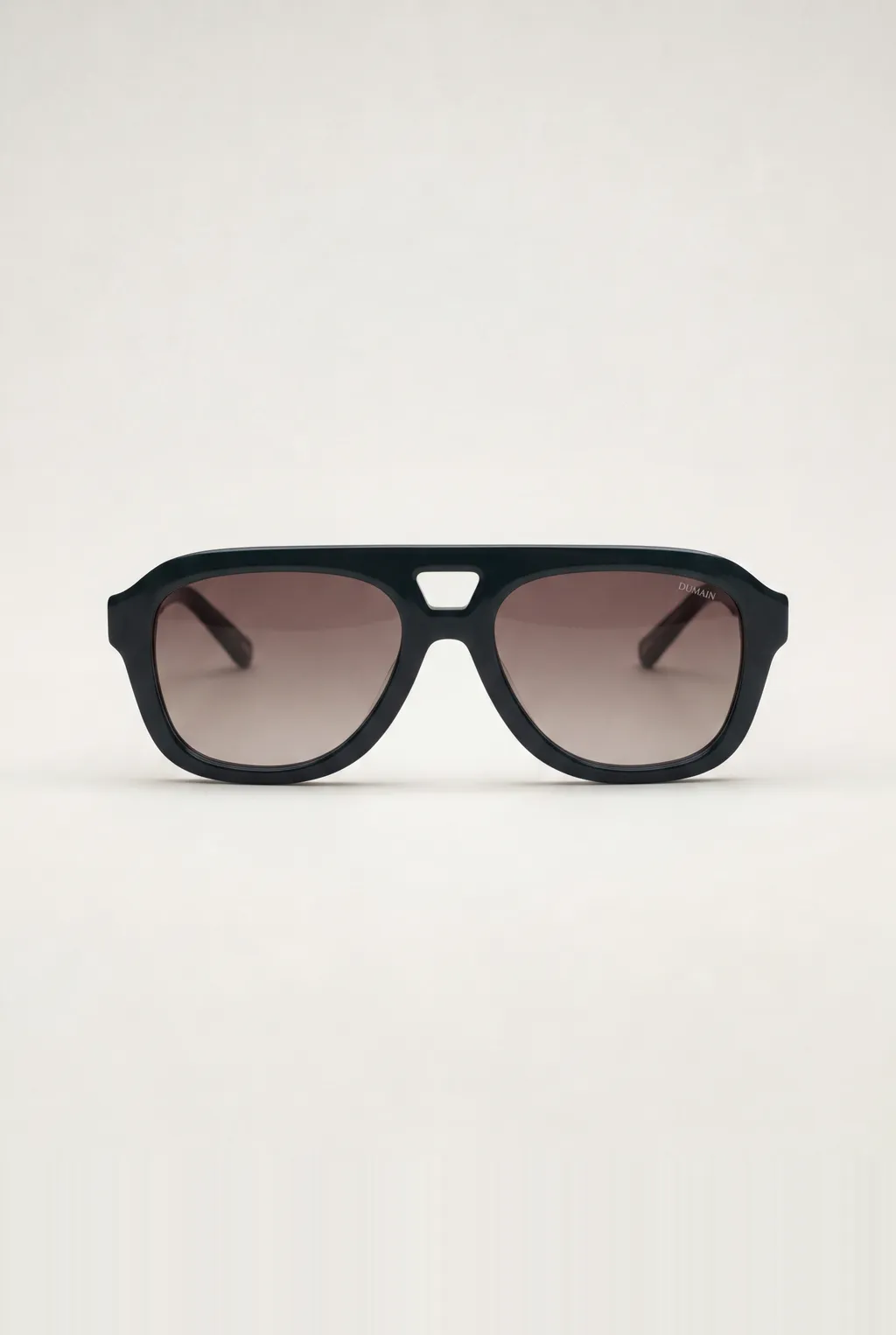 Black aviator sunglasses with brown gradient lenses on a light grey background