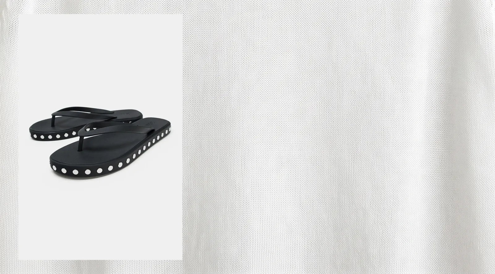 Black studded flat sandals beside a swatch of white linen