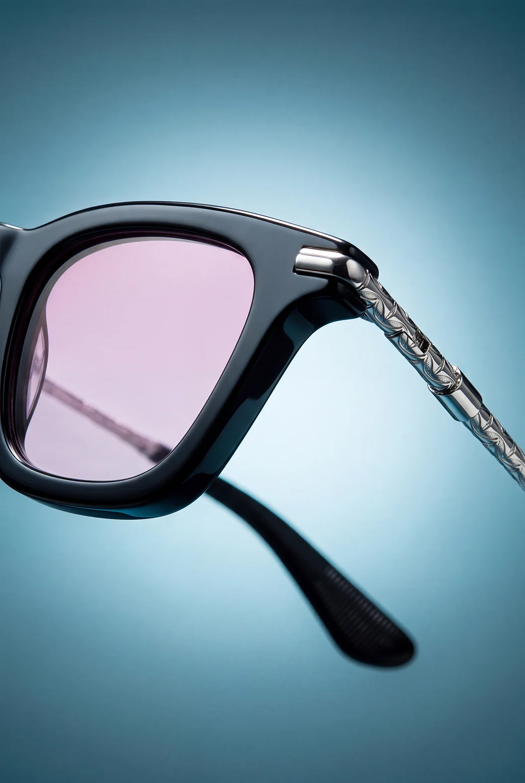 Hills Eyewear — Square Frame Collection: close-up of a black square frame with pink gradient lenses and an engraved silver temple, on a teal gradient background
