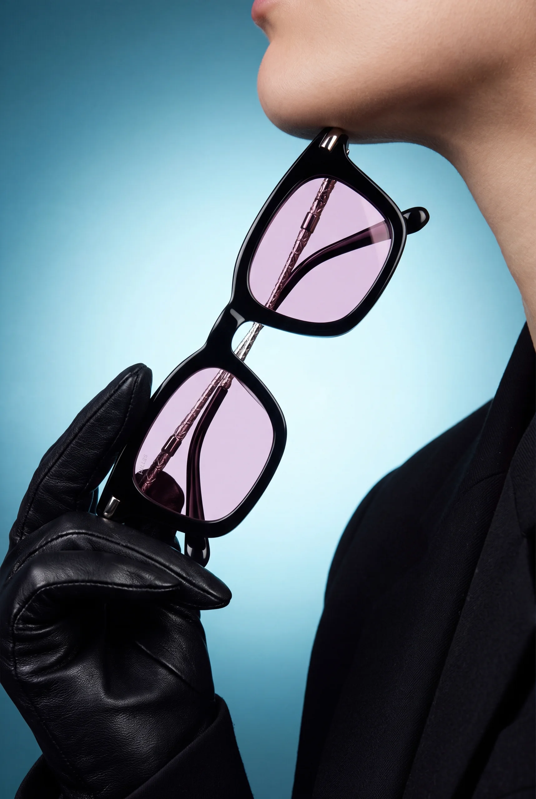 Hills Eyewear hero — black-frame sunglasses with pink gradient lenses held in a gloved hand